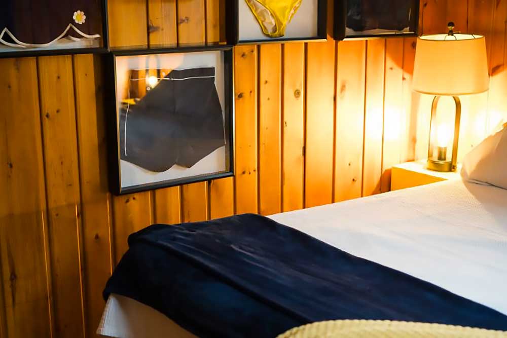 Huron-bedroom-3 A cozy bedroom with wood-paneled walls, soft lighting from a bedside lamp, and a neatly made bed, ideal for a relaxing getaway at South Shore Resort and Retreats, offering peaceful and scenic lodging in West Michigan.| South Shore Resort & Retreats in West Michigan