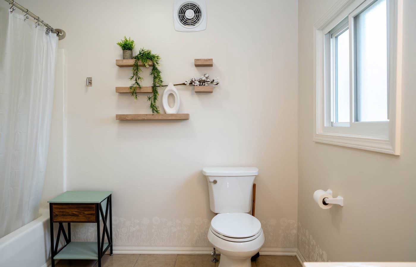 The-lodge-image-9 A serene bathroom featuring a white toilet, floating wooden shelves with green plants, and soft lighting, offering a peaceful retreat atmosphere ideal for a Lake Michigan getaway at South Shore Resort and Retreats.| South Shore Resort & Retreats in West Michigan
